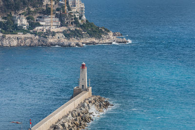 Lighthouse by sea against blue sky