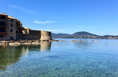 Scenic view of sea by buildings against sky