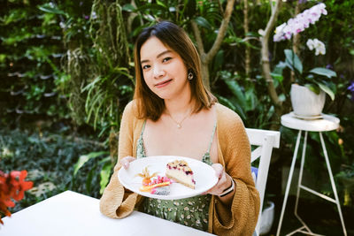 Portrait of smiling young woman standing against trees