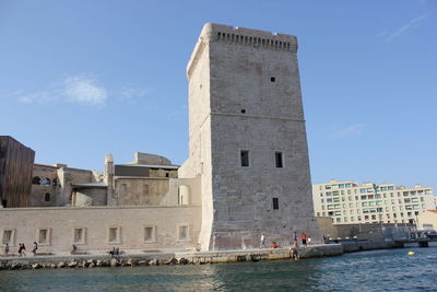 View of buildings by sea against sky in city