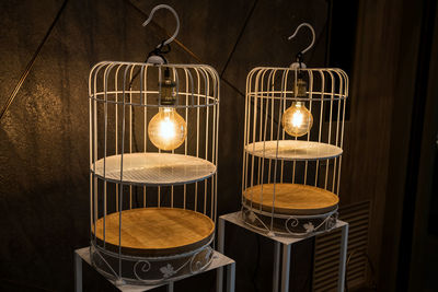 Close-up of illuminated candles on table against wall