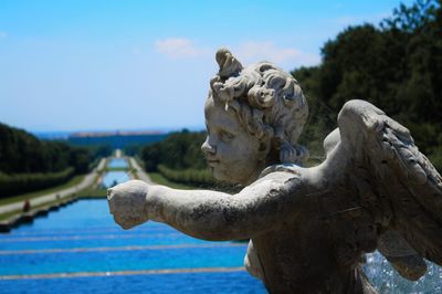 Close-up of old statue by water against sky