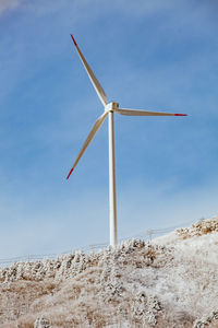 Low angle view of windmill on field against sky