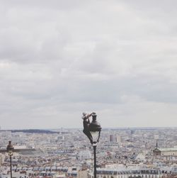 Man with umbrella against buildings in city against sky