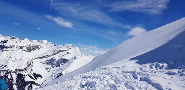 Scenic view of snowcapped mountains against blue sky