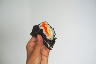 Close-up of hand holding ice cream over white background