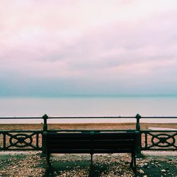 Railing by sea against sky during sunset