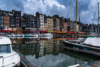 Boats in harbor against cloudy sky