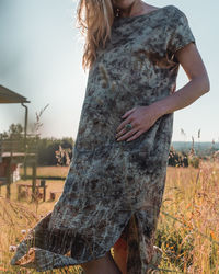 Midsection of woman standing on field against sky