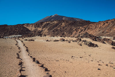 Scenic view of desert against clear blue sky