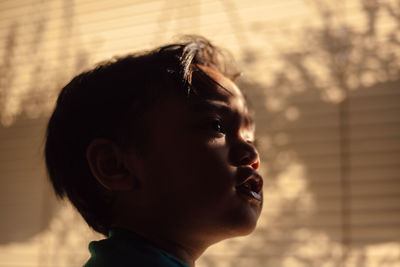 Close-up of boy against wall during sunset