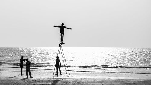 People standing on beach against clear sky