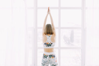 Girl in a sports uniform does exercises, physical exercises, yoga and stretches at home