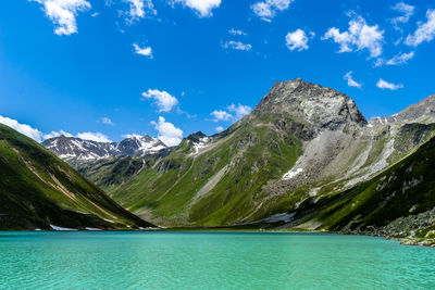 Scenic view of lake by mountains against blue sky