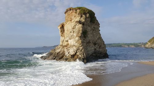 Rock formation on beach against sky