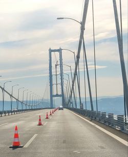 Road by suspension bridge against sky