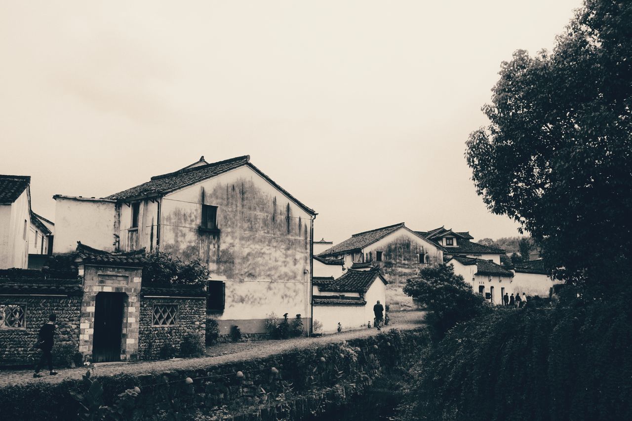 HOUSES ON FIELD BY BUILDINGS AGAINST SKY