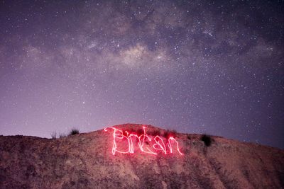 View of text written on desert against sky at night