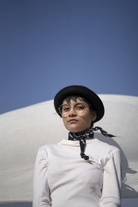 Portrait of woman wearing hat against sky in winter