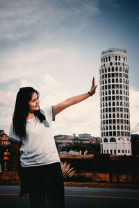 Full length of young woman standing against buildings in city