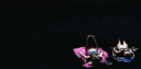 High angle view of women lying down against black background