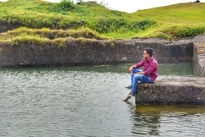 Full length of man sitting by lake