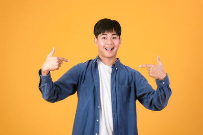 Portrait of smiling boy standing against yellow background