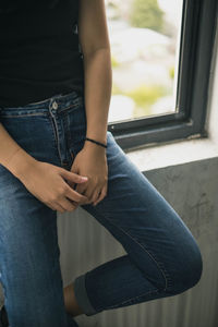 Low section of woman leaning on window