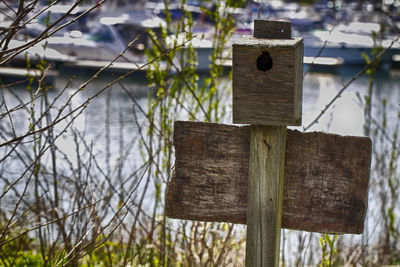 Close-up of birdhouse on wooden fence by lake