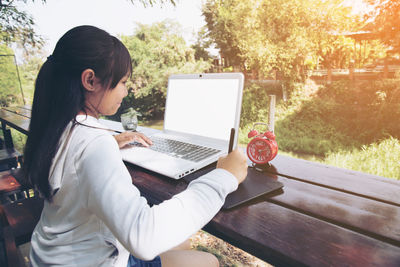 Close-up of girl using digitized tablet with laptop on table 