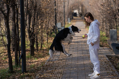 Side view of man with dog standing in forest