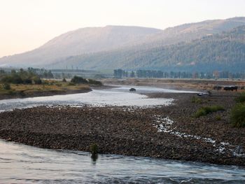 Scenic view of river by mountains against sky