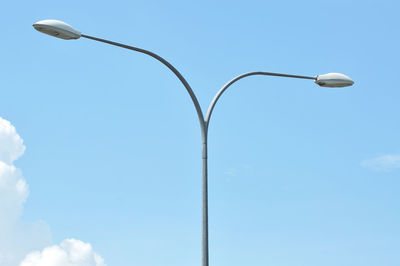 Low angle view of street lights against blue sky