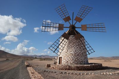 Traditional windmill on landscape against sky