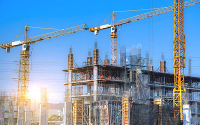 Low angle view of cranes against sky