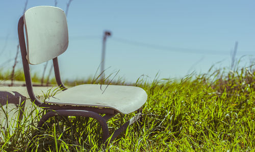 Close-up of chair on field against clear sky