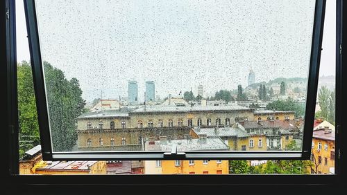 Buildings against clear sky seen through glass window