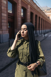 Young woman standing against building