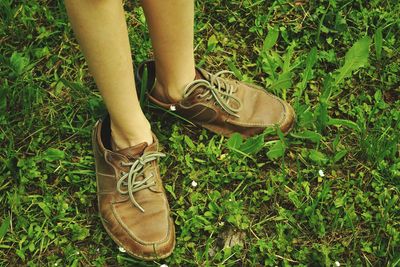 Low section of man wearing brown leather boots while standing on field