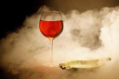 Wineglass and ashtray amidst smoke