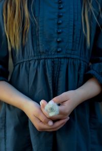 Midsection of girl holding dandelion