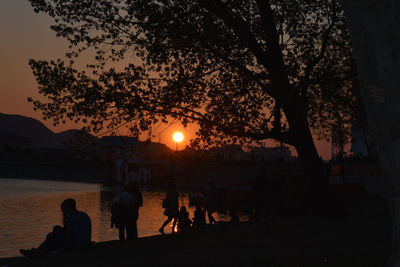 Silhouette people by tree against sky during sunset