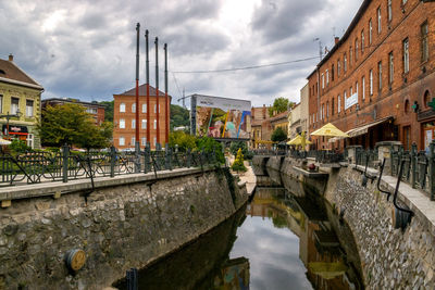 Canal amidst buildings in city against sky