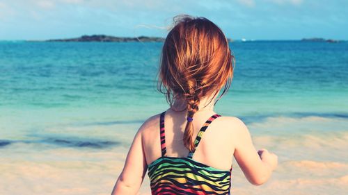 Rear view of woman at beach against sky