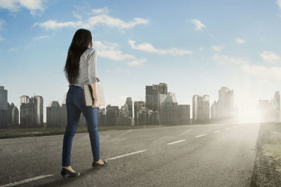 Rear view of businesswoman walking on road in city