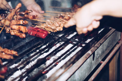 Cropped hands preparing food on barbecue grill