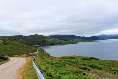 Scenic view of road by lake against sky