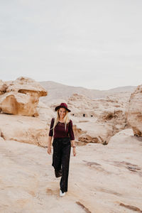 Young woman walking at desert against sky