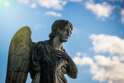 Low angle view of ancient angel statue against sky