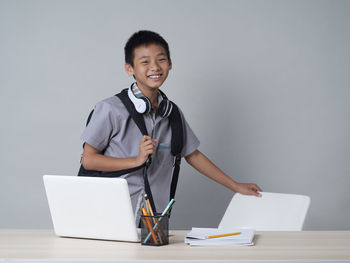 Portrait of smiling young man using phone while standing on table